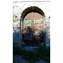 Il portale visto frontalmente. L'intonaco originario manca in vaste porzioni della struttura, la porta è arrugginita e presenta scritte deturpanti. (Pietro Falco) 