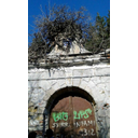 Fronte del portale. La foto rappresenta efficacemente le sue condizioni attuali: la porta in ferro è ricoperta di graffiti e scritte, l'edicola è sovrastata dalla vegetazione e i mattoni sono sgretolati (Riccardo Ferro)